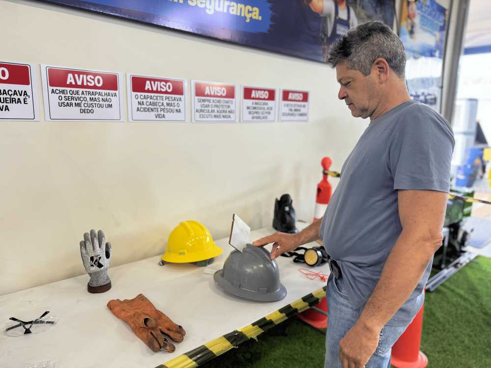 Homem analisando equipamentos de proteção individual danificados em cima de uma mesa.